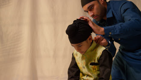 Foto-De-Estudio-De-Un-Padre-Atando-Un-Turbante-En-La-Cabeza-De-Su-Hijo-Sikh-Que-Lleva-Un-Chaleco-Tradicional,-Como-Se-Muestra-En-La-Secuencia,-Parte-9-De-10